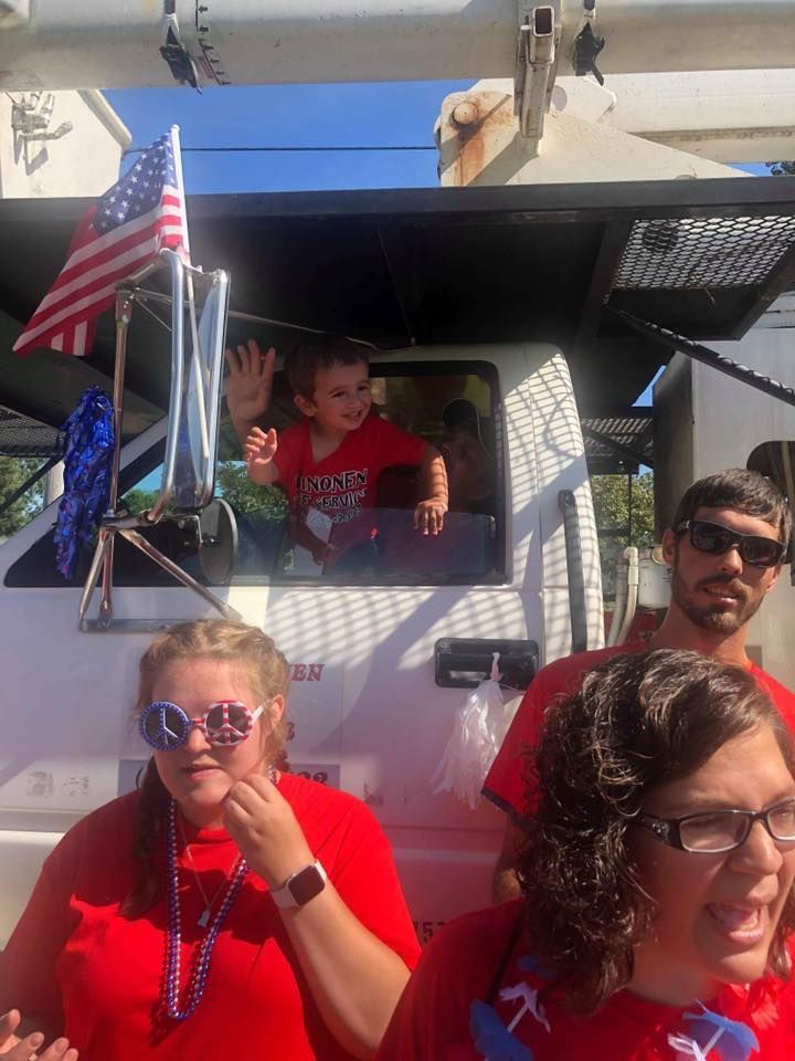 A group of people in red shirts are standing in front of a truck.