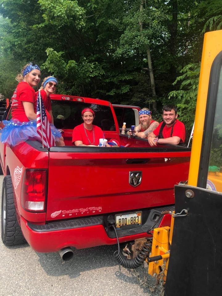 A group of people are sitting in the back of a red truck.