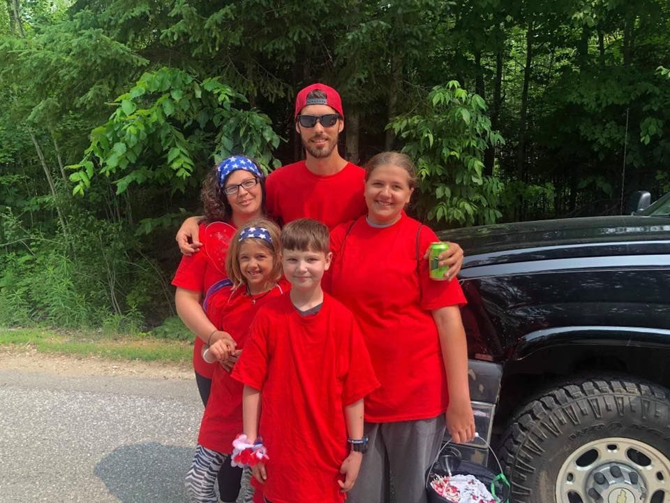 A family is posing for a picture in front of a truck.
