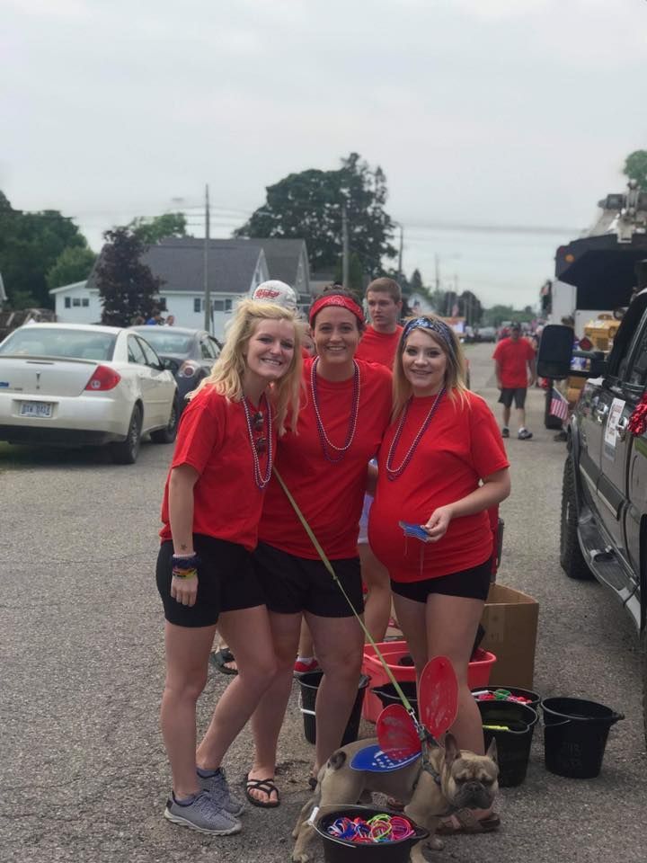 A group of women in red shirts are standing next to a dog.