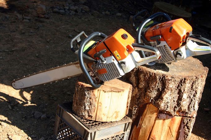 Two chainsaws are sitting on a tree stump