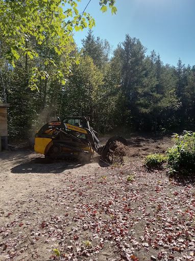 A yellow tractor is digging a hole in a dirt field.