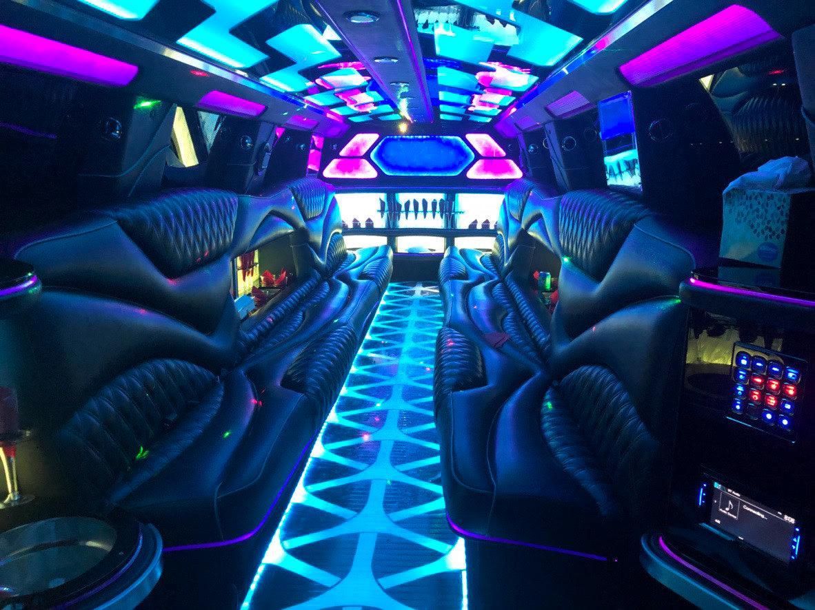 The inside of a limousine is lit up with purple and blue lights.
