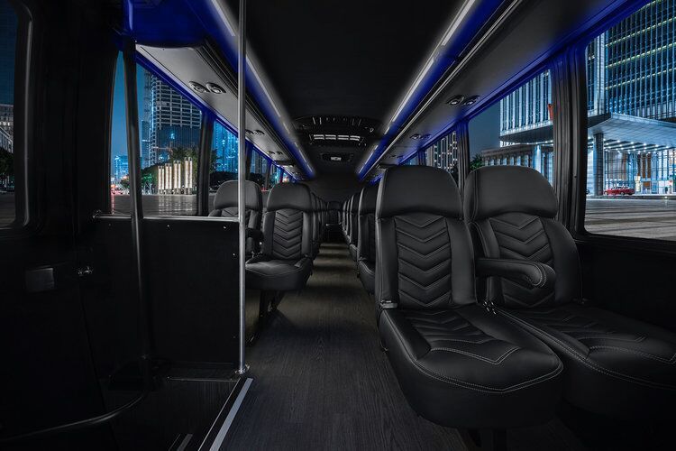 The inside of a bus with black seats and a city in the background.