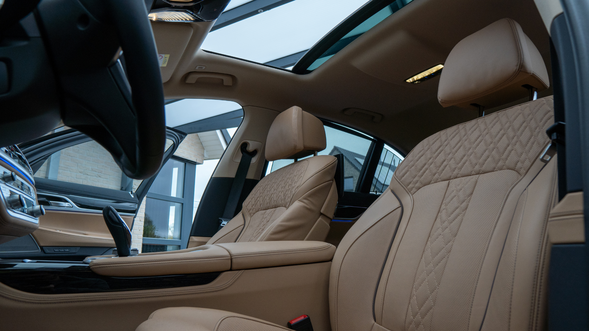 A man in a suit is sitting in the back seat of a car using a laptop and talking on a cell phone.