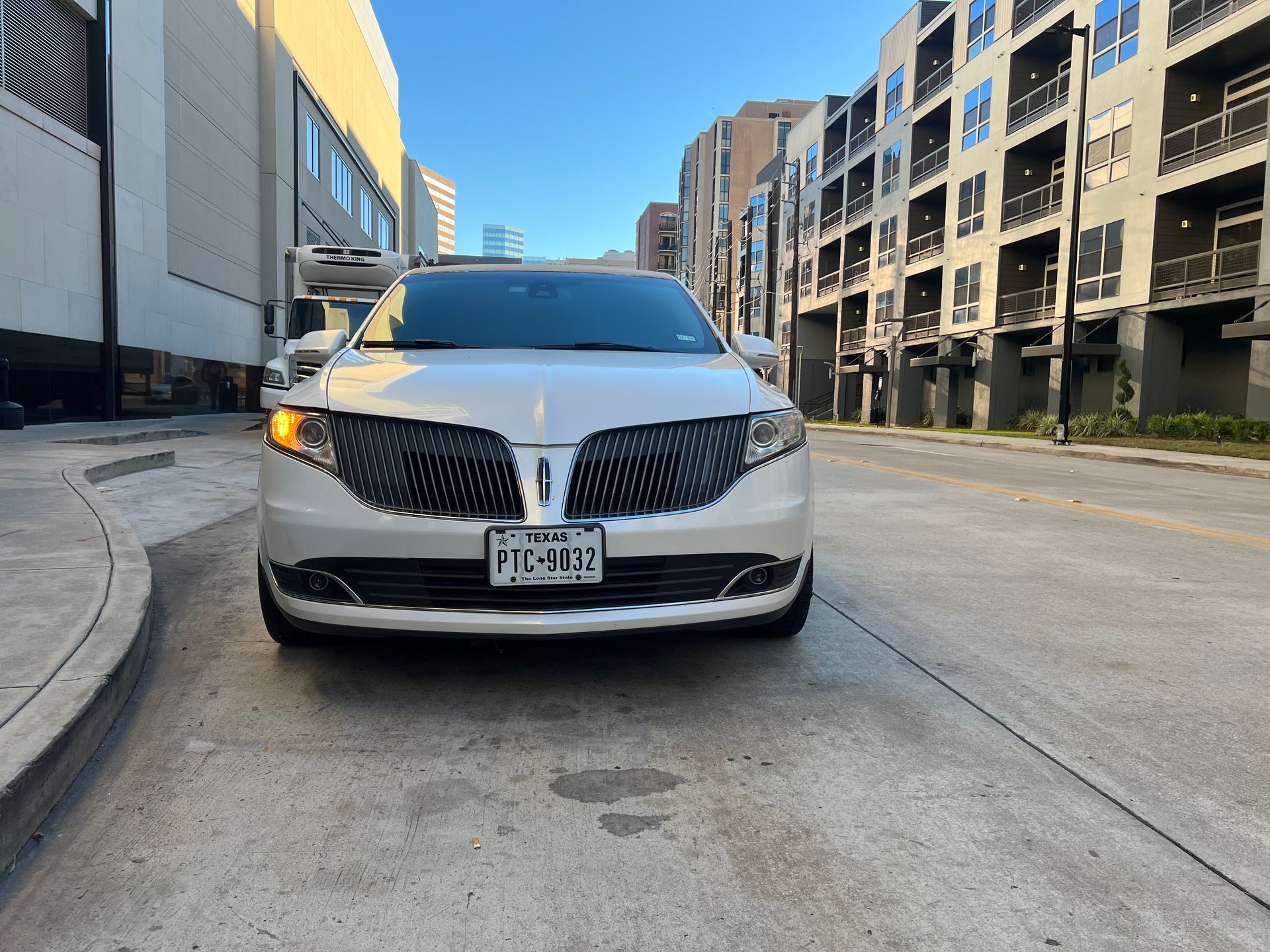 A white lincoln continental is parked on the side of the road