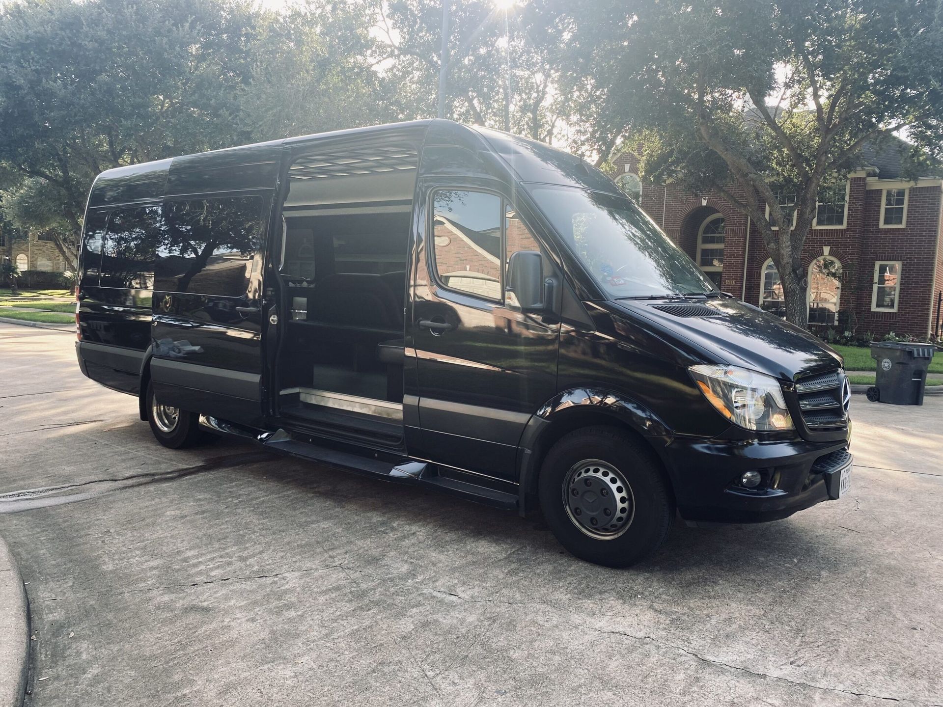 A black van is parked in a driveway in front of a house.