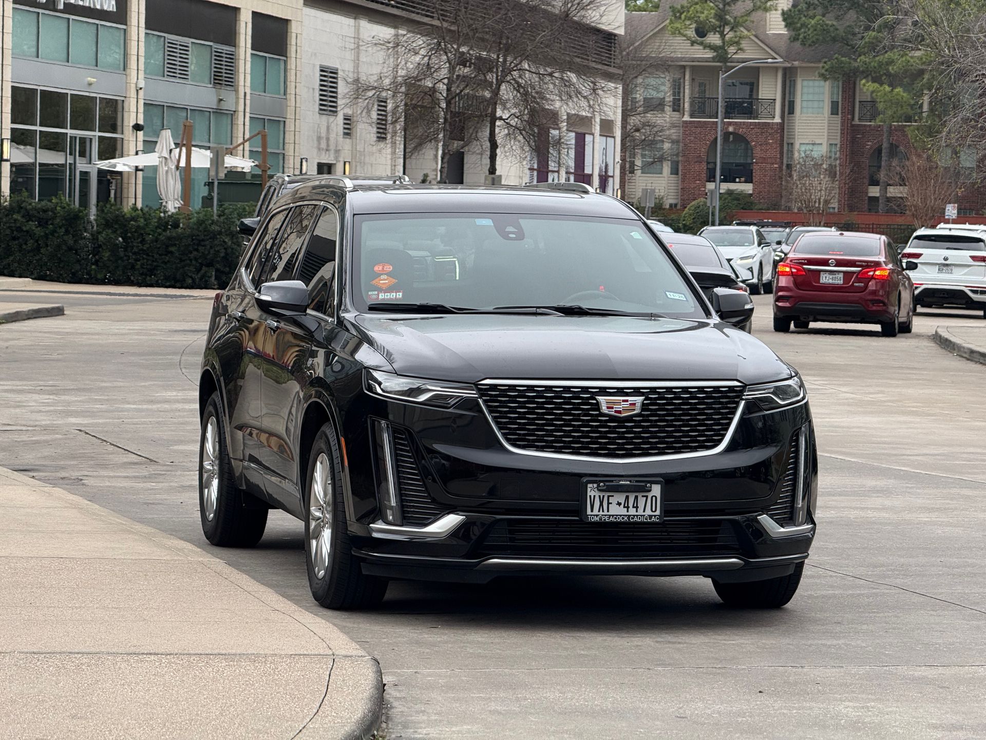 A black cadillac is driving down a city street.