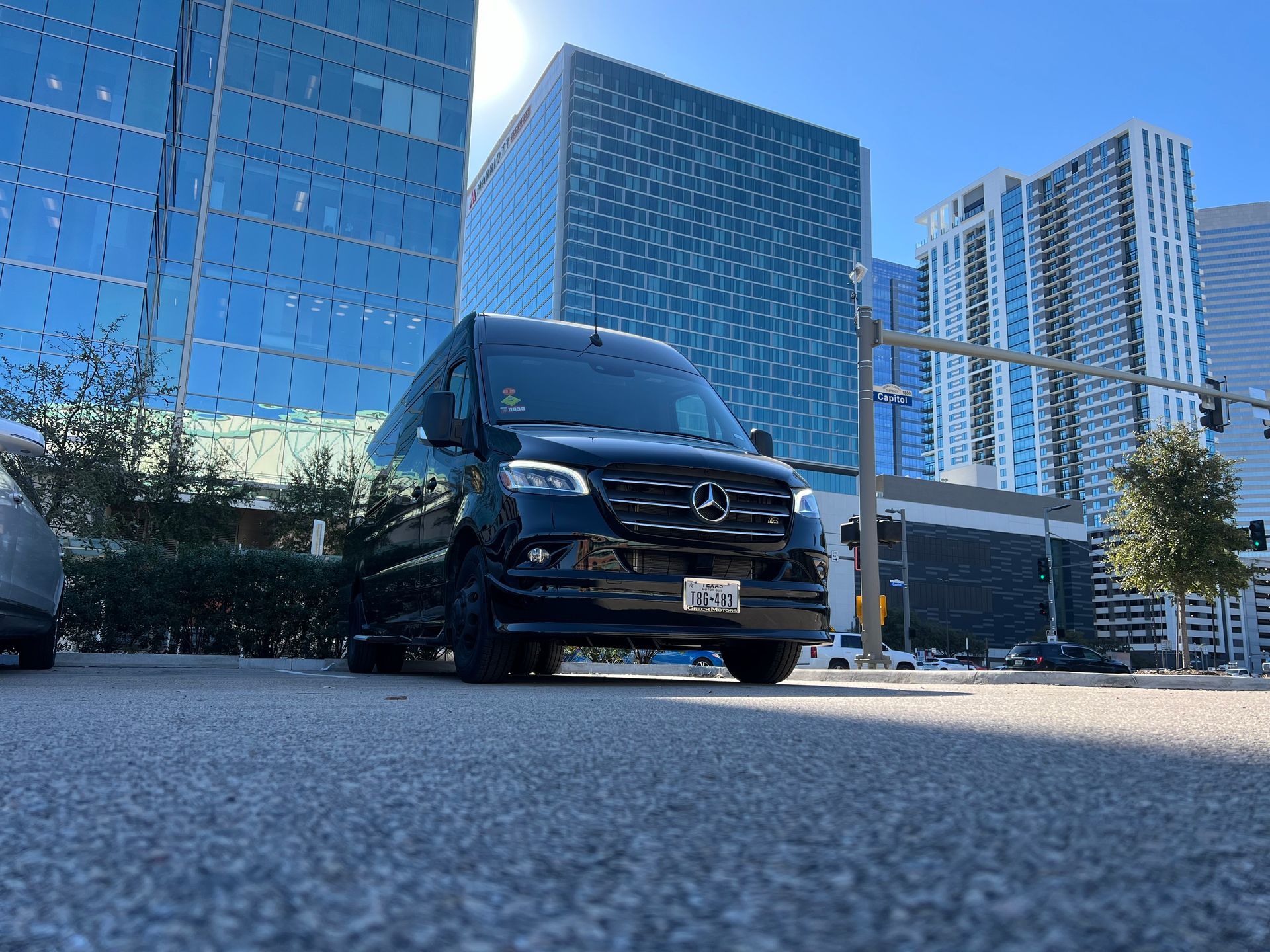 Black van parked in front of modern buildings on a sunny day.