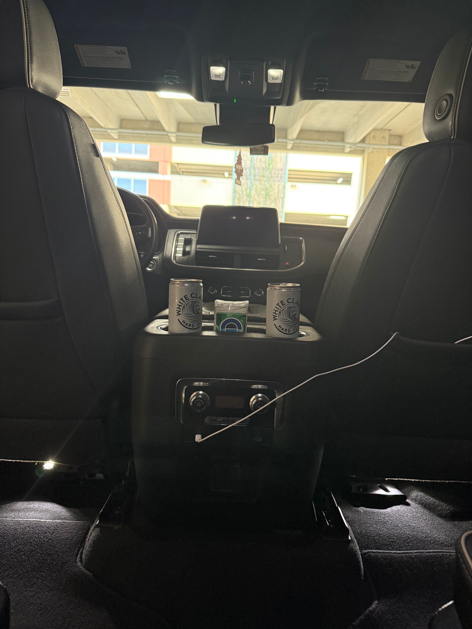 The back seat of a car with two cups on it