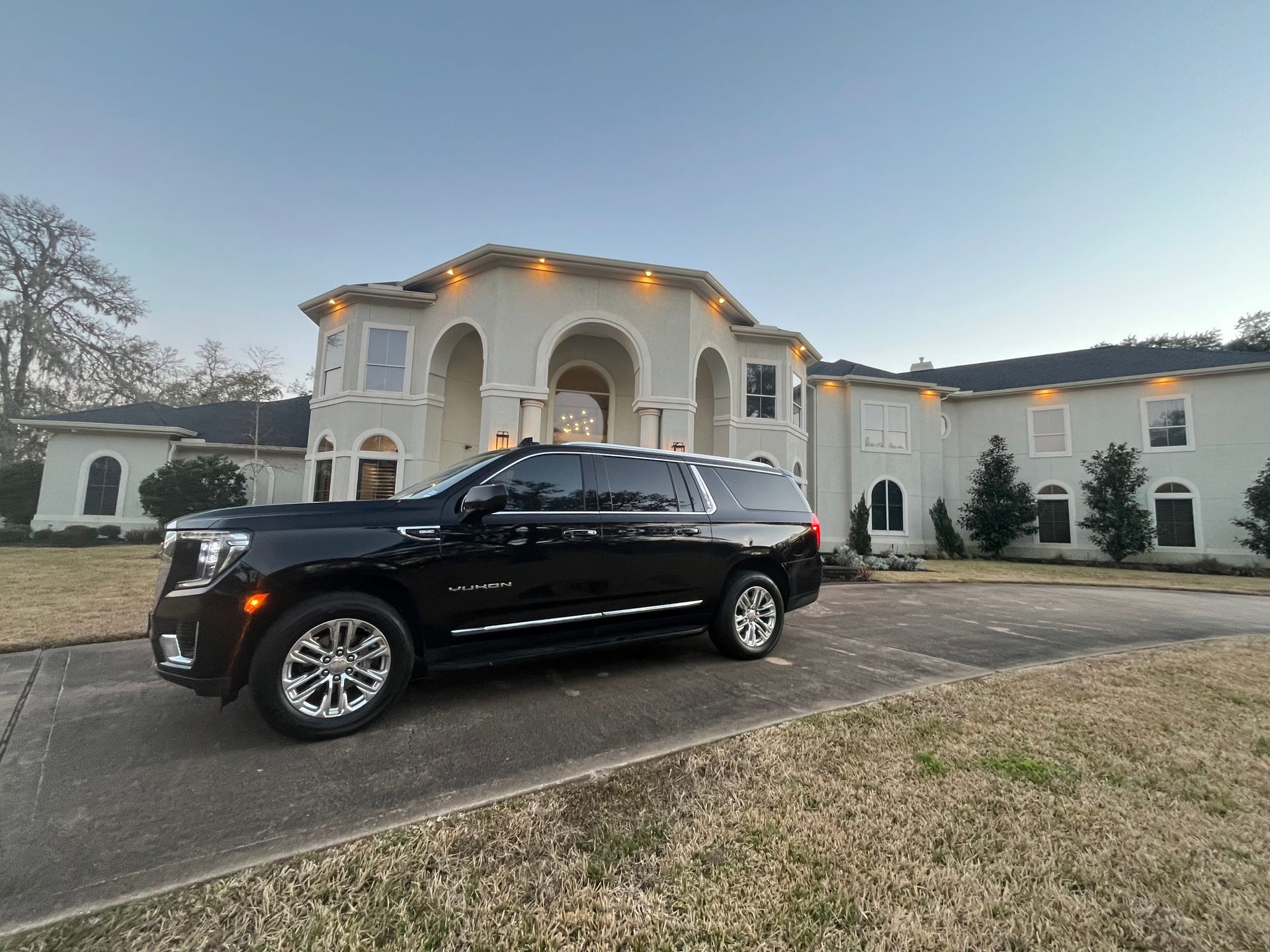A black suv is parked in front of a large house.