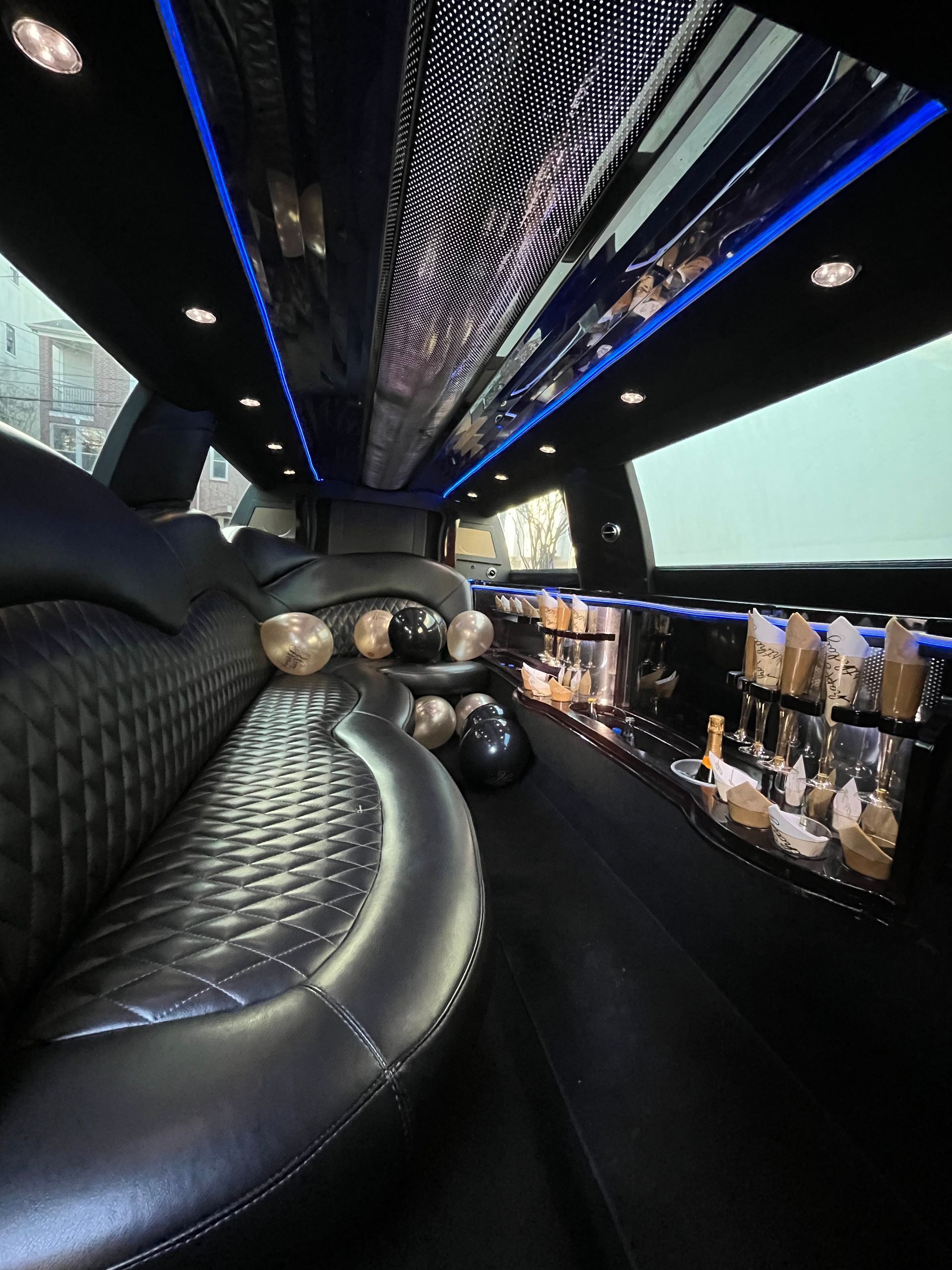 The inside of a limousine with a long couch and a bar.