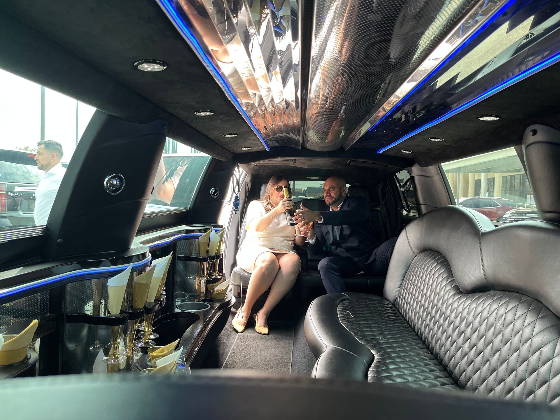 A man and a woman are sitting in the back seat of a limousine.