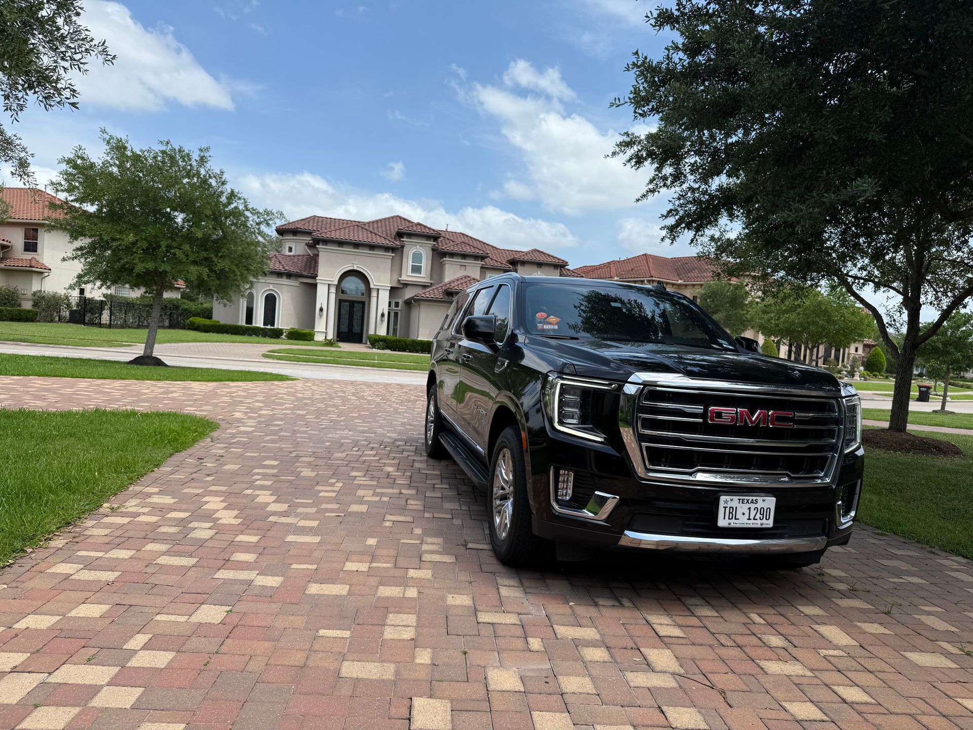 A black gmc truck is parked on a brick driveway in front of a house.