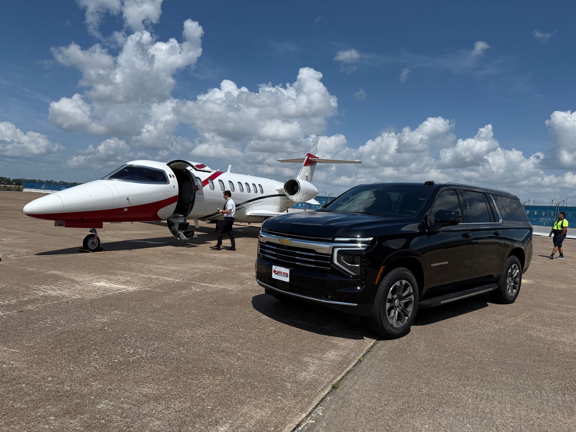A black suv is parked next to a small jet on a runway.