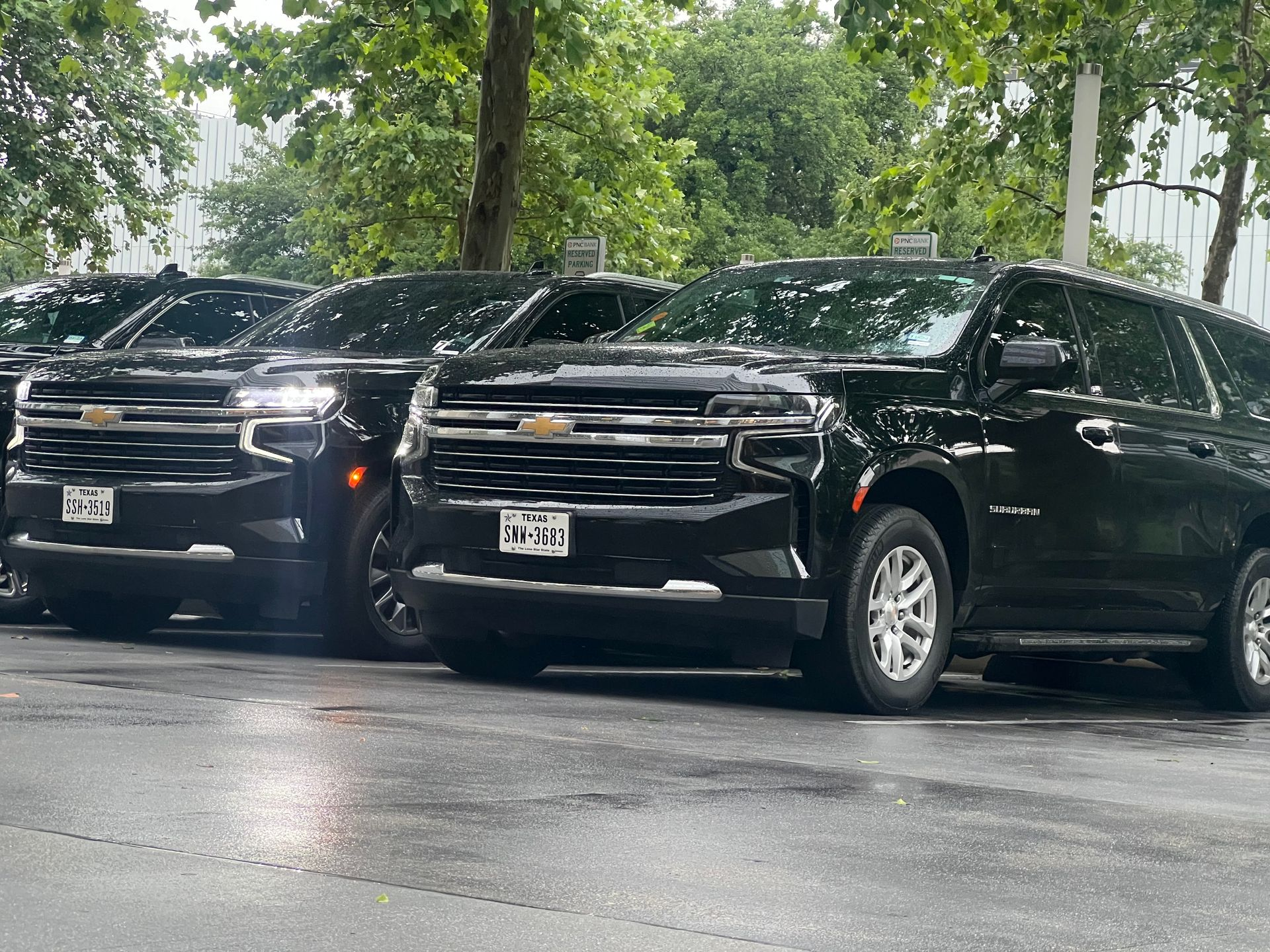 Black Chevrolet SUVs parked outdoors on a wet day.