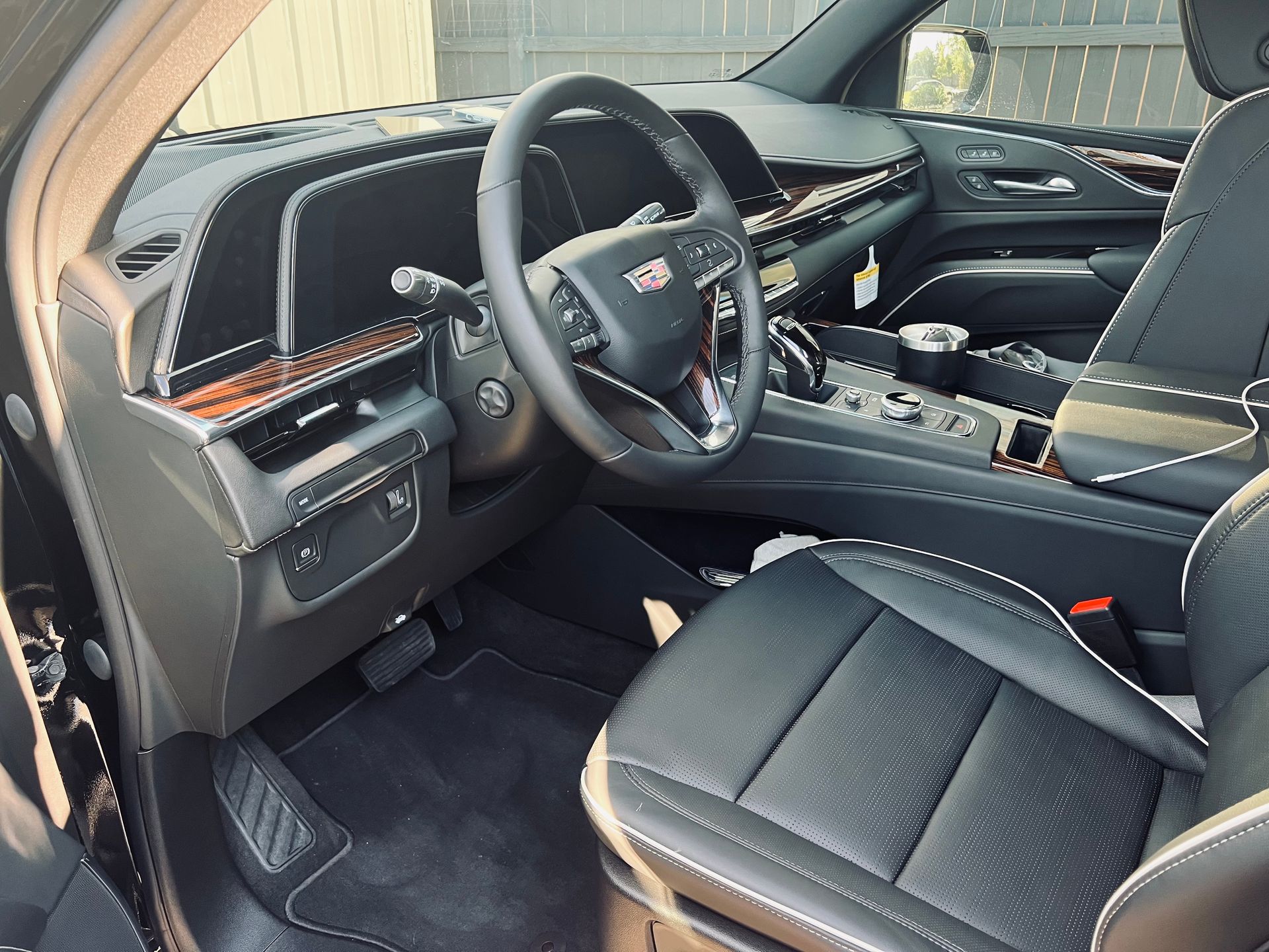 Black Cadillac SUV interior, steering wheel, dashboard, leather seats, wood trim, and center console.