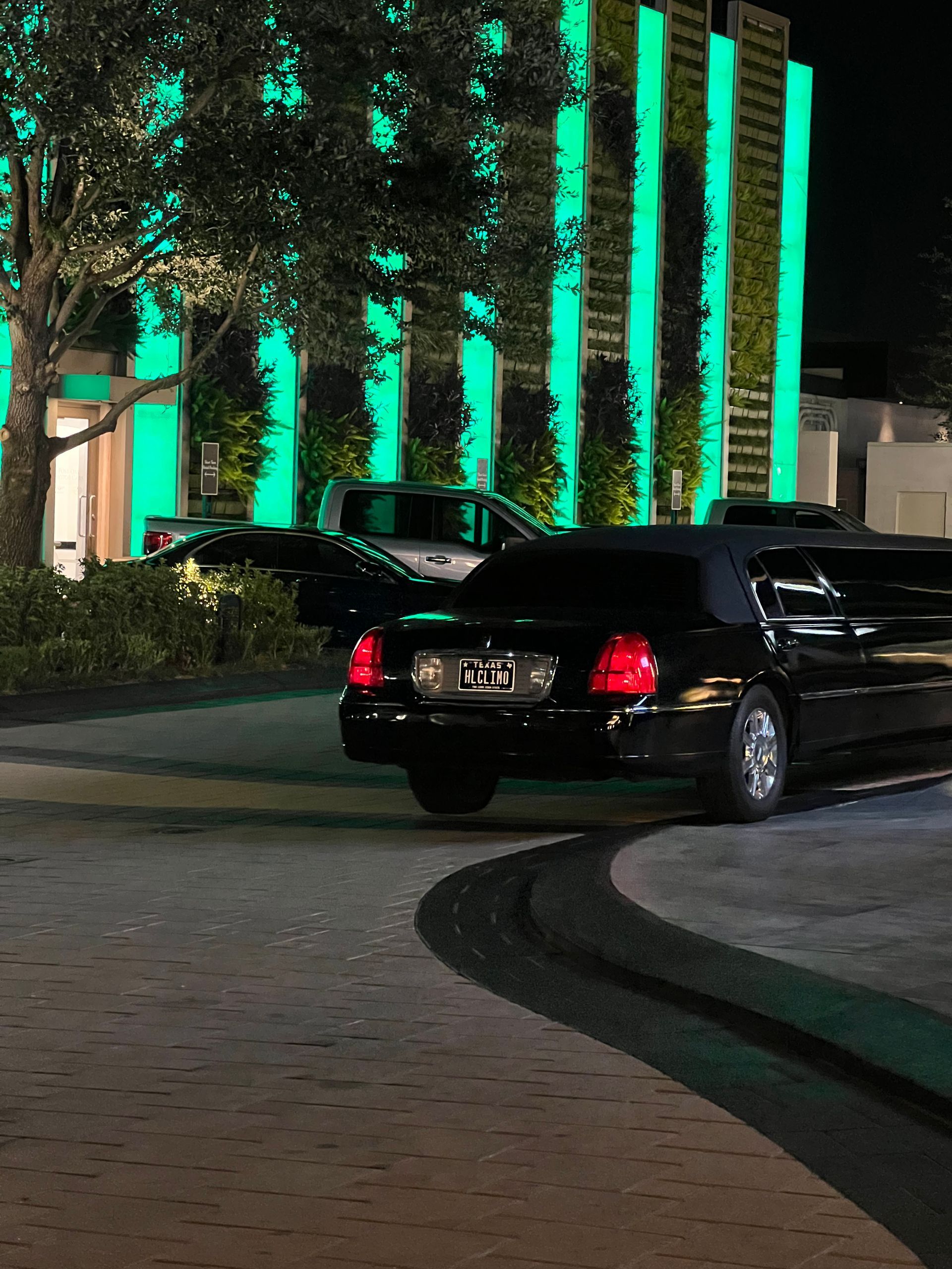 A black car is parked in front of a building with green lights