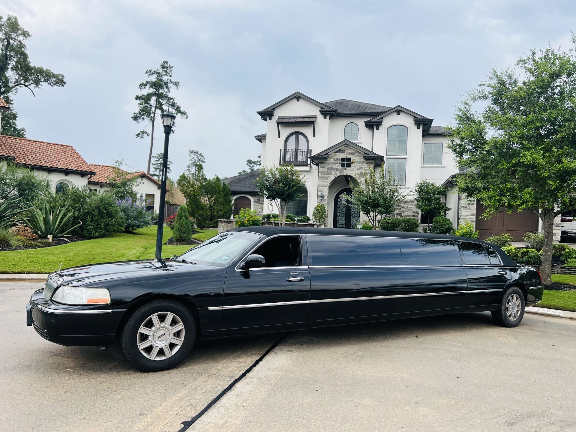 A black limousine is parked in front of a large house.
