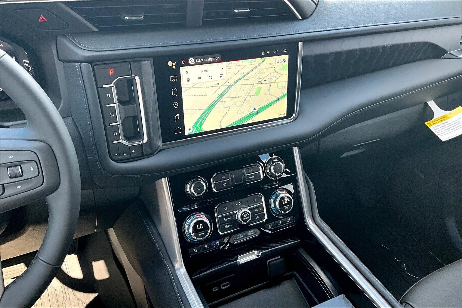 Car interior showing navigation on a central touchscreen, with climate controls below, black and silver.