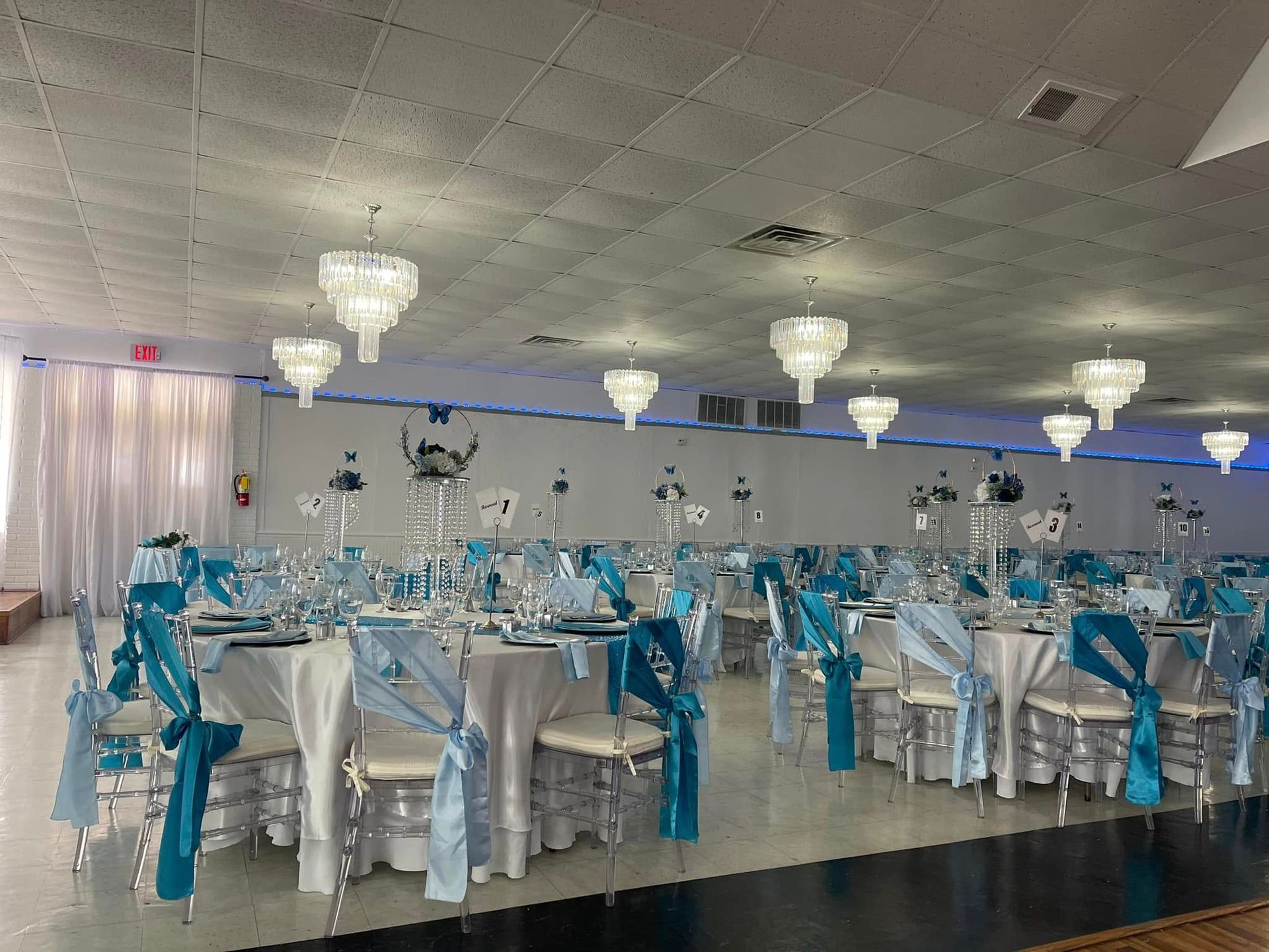 A large room with tables and chairs set up for a wedding reception.