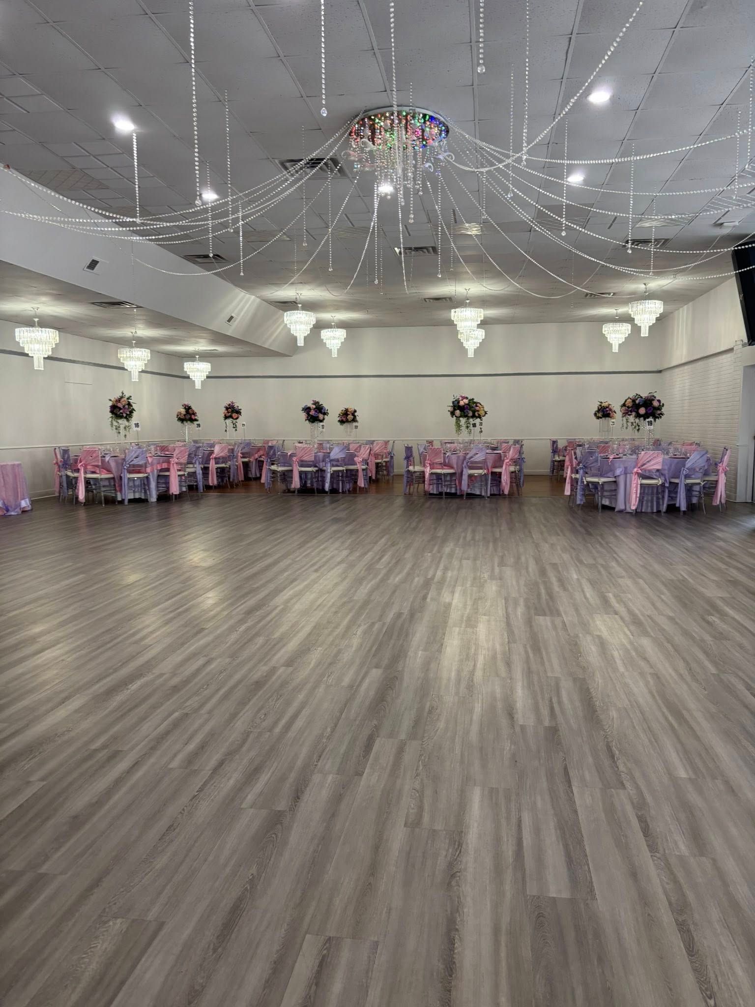 A large empty ballroom with tables and chairs set up for a wedding reception.