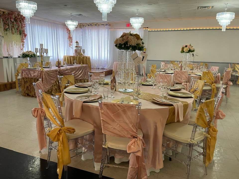 A large room with tables and chairs set up for a wedding reception.