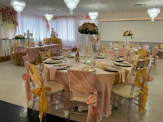 A large room with tables and chairs set up for a wedding reception.