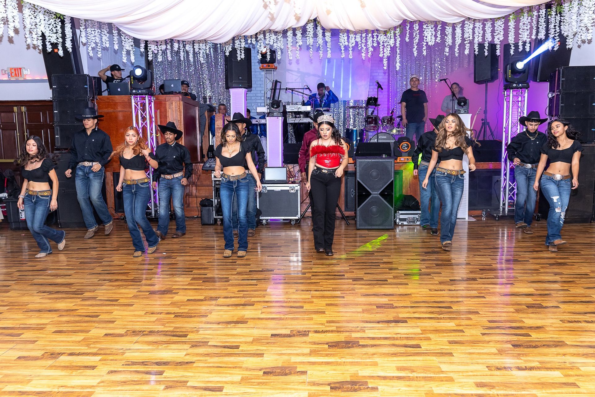 A group of people are dancing on a wooden dance floor.
