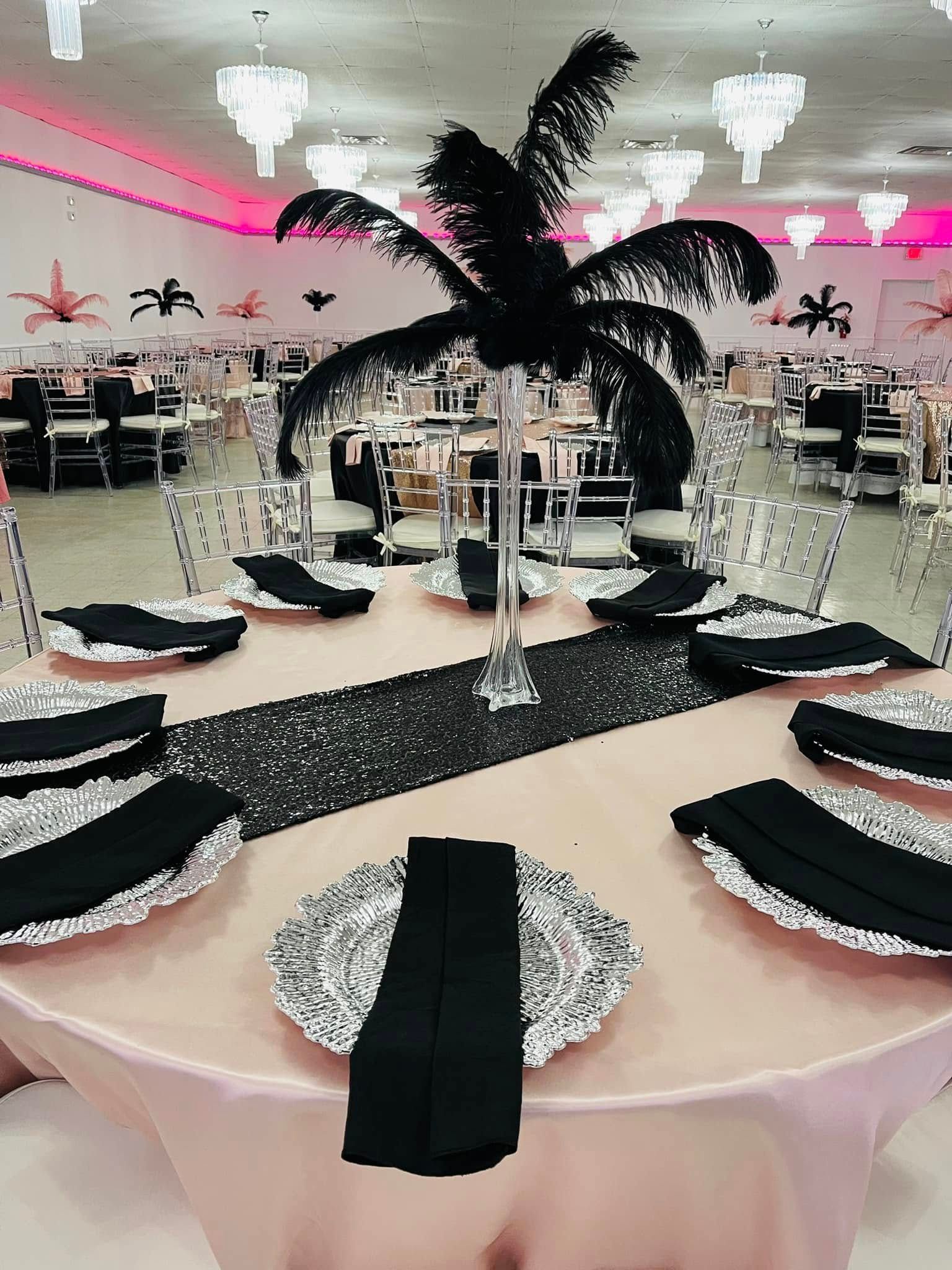 A table set for a wedding reception with black and silver plates and napkins.