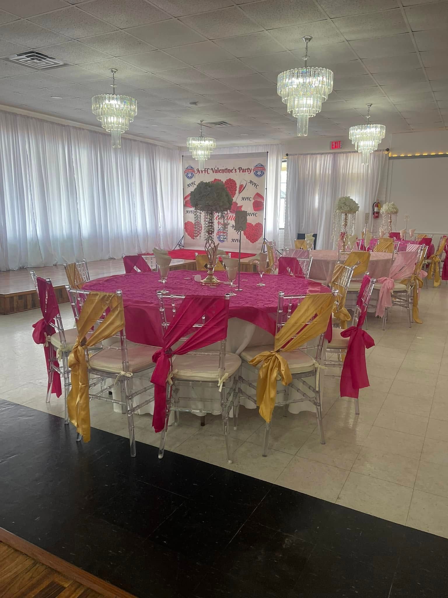 A large room with tables and chairs set up for a wedding reception.