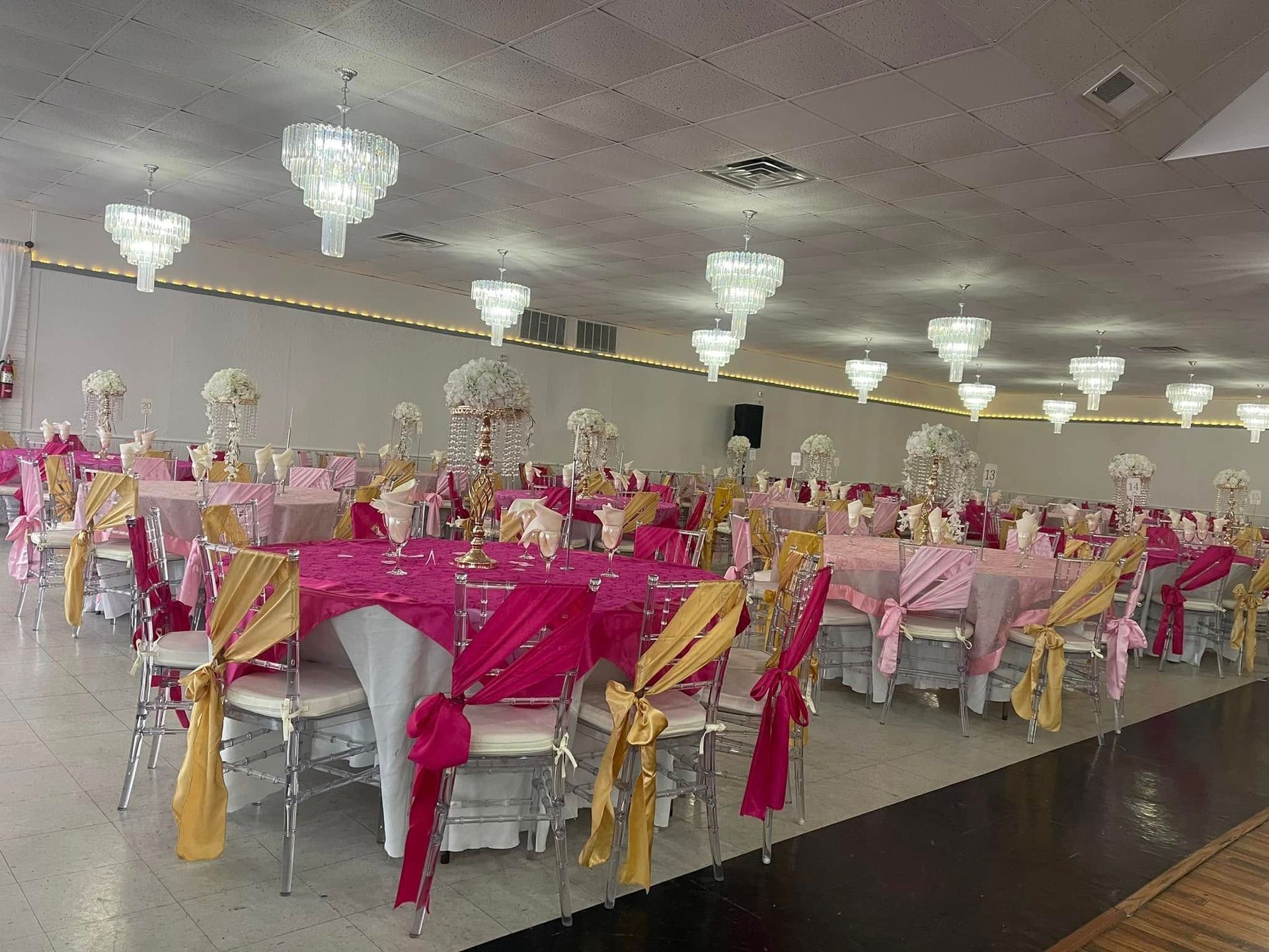A large room filled with tables and chairs decorated for a wedding reception.