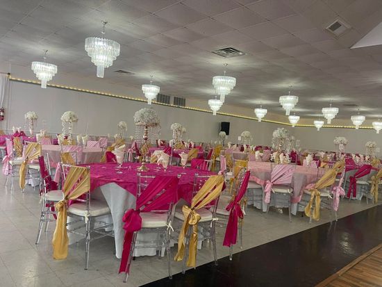 A large room filled with tables and chairs decorated for a wedding reception.