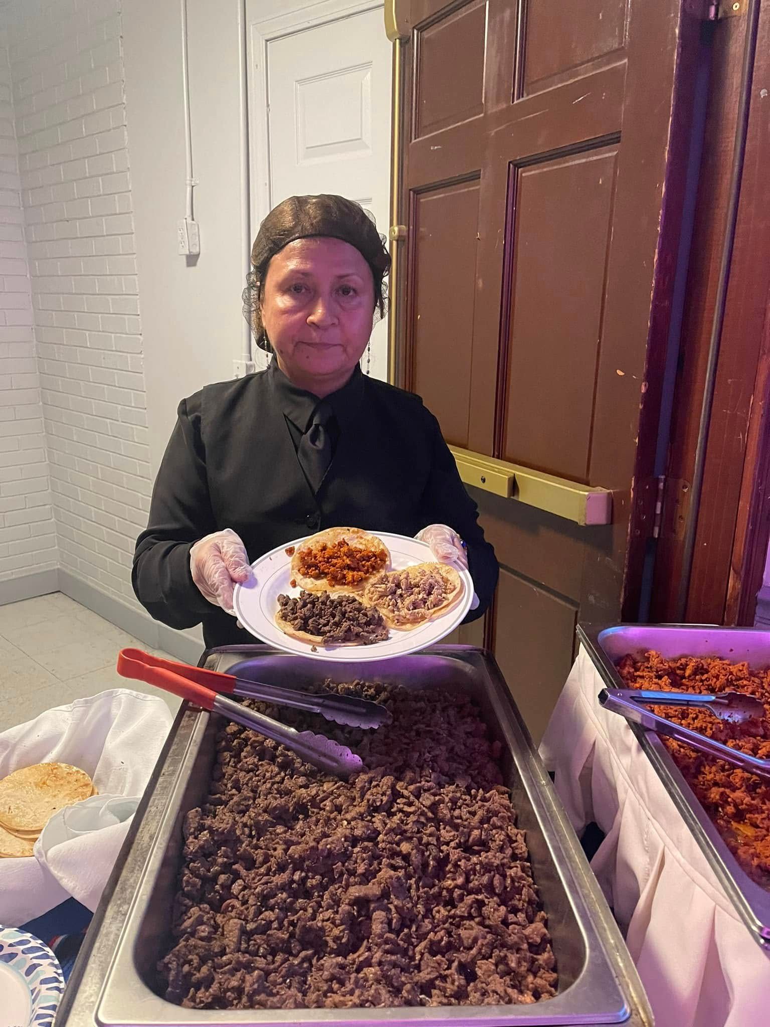 A woman is holding a plate of food in front of a buffet.