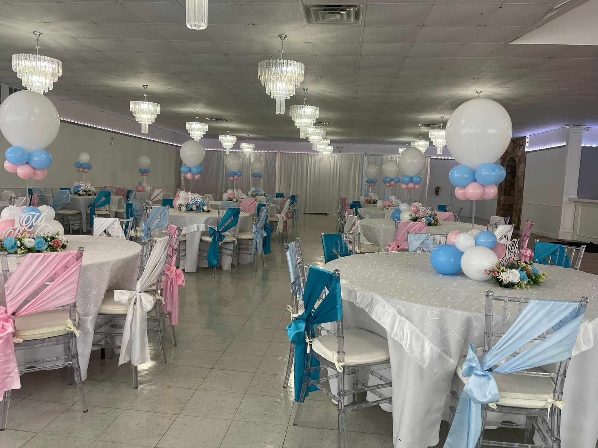 A large room filled with tables and chairs decorated for a baby shower.
