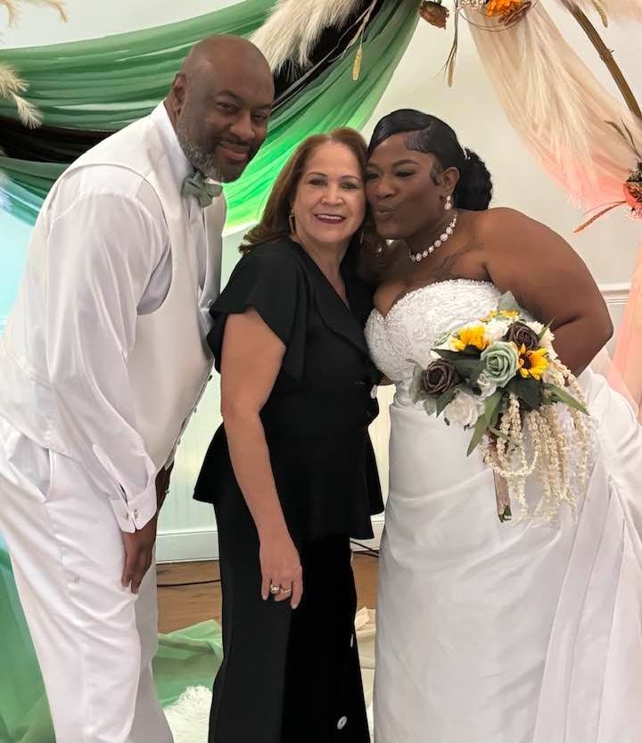 A bride and groom pose for a picture with their wedding planner