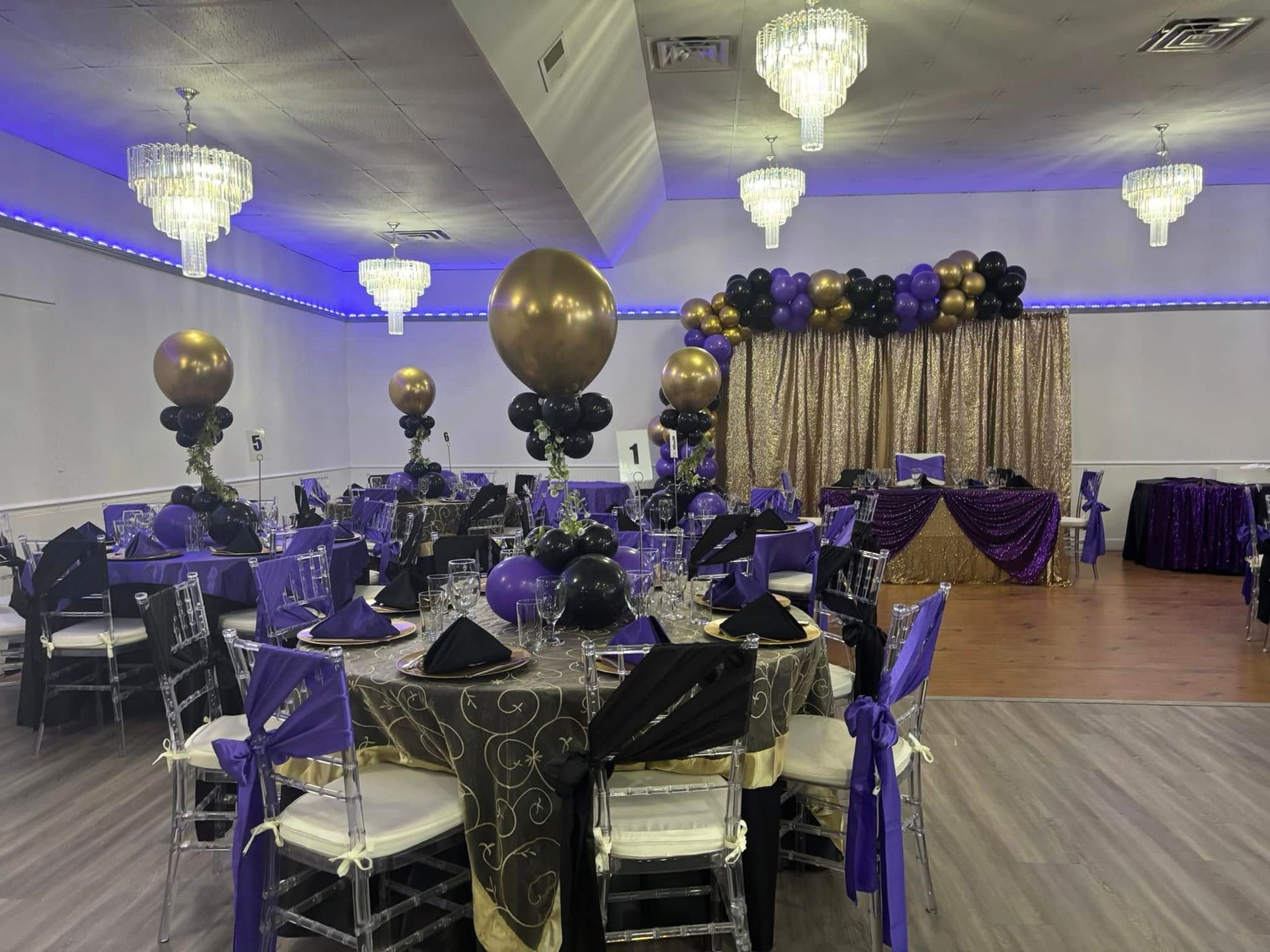 A large room decorated for a party with tables and chairs and balloons.