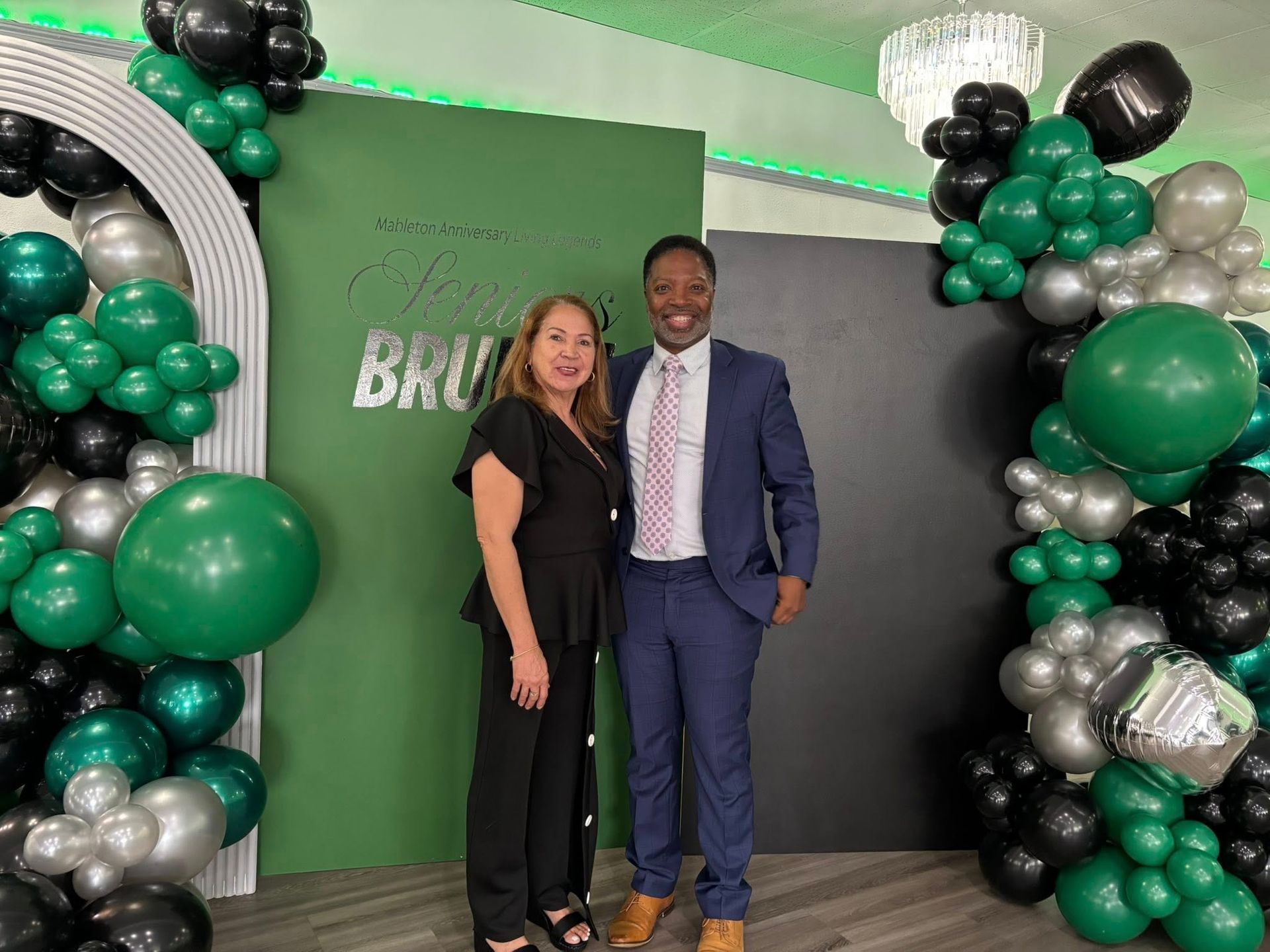 A man and a woman are standing next to each other in front of balloons.