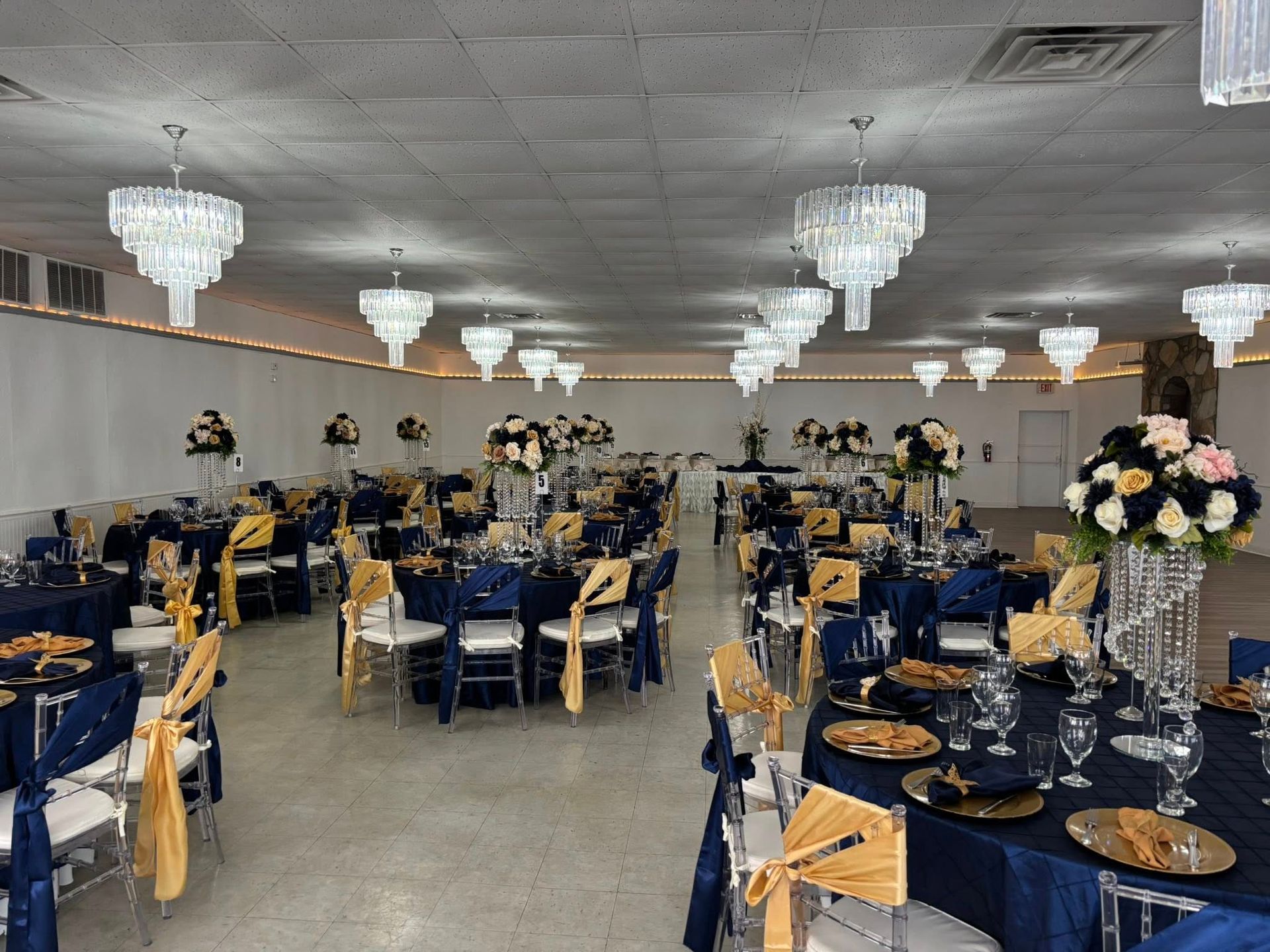 A large room with tables and chairs set up for a wedding reception.