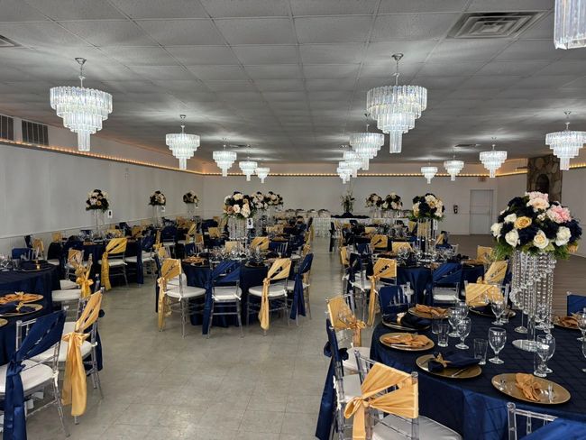 A large room with tables and chairs set up for a wedding reception.