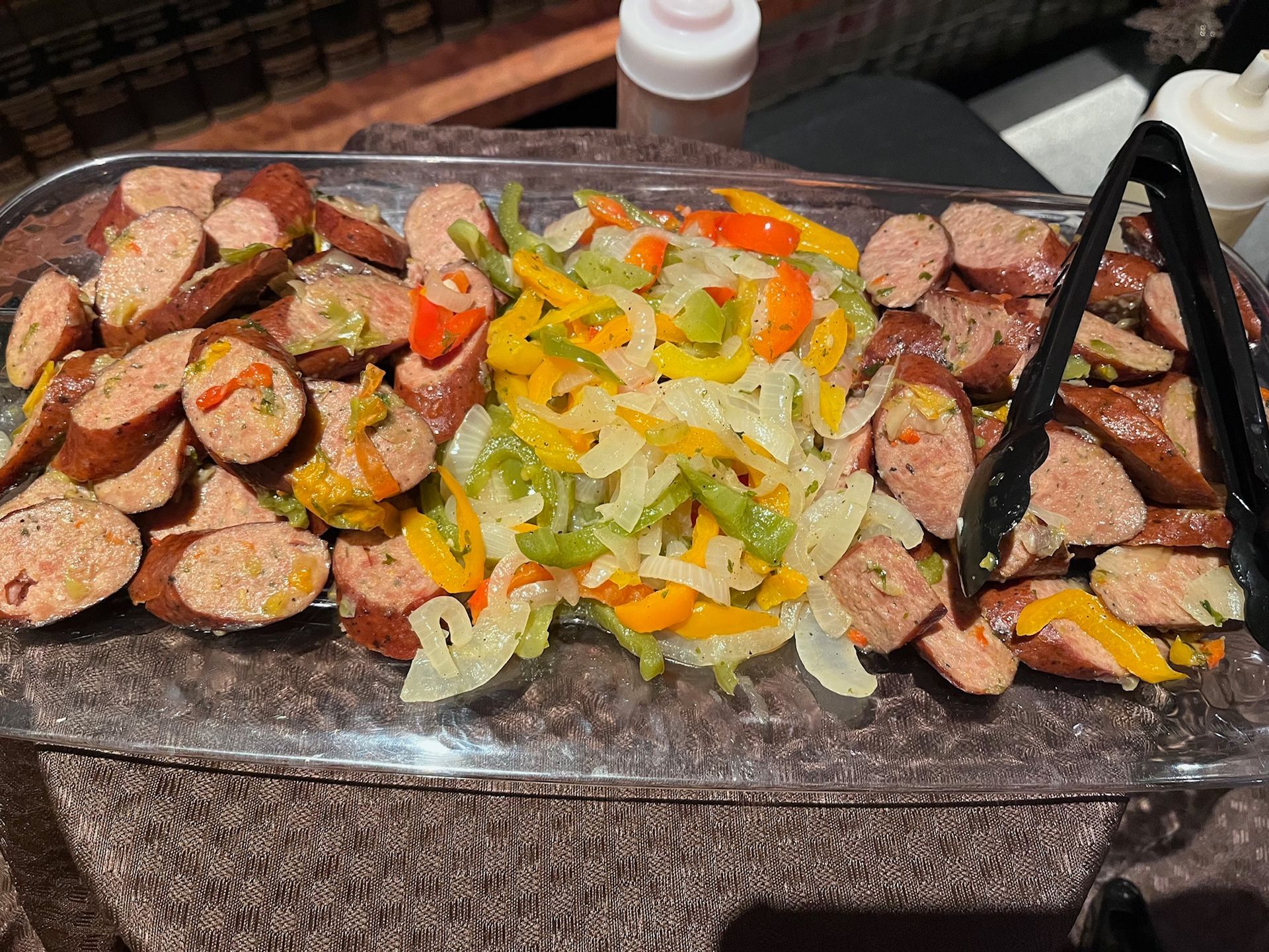 Sliced sausage with sauteed peppers and onions on a platter.