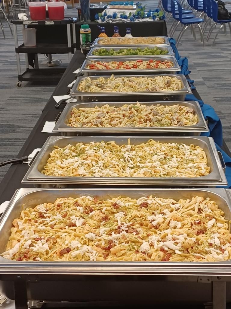 Buffet table with various pasta dishes, arranged in silver warming trays.