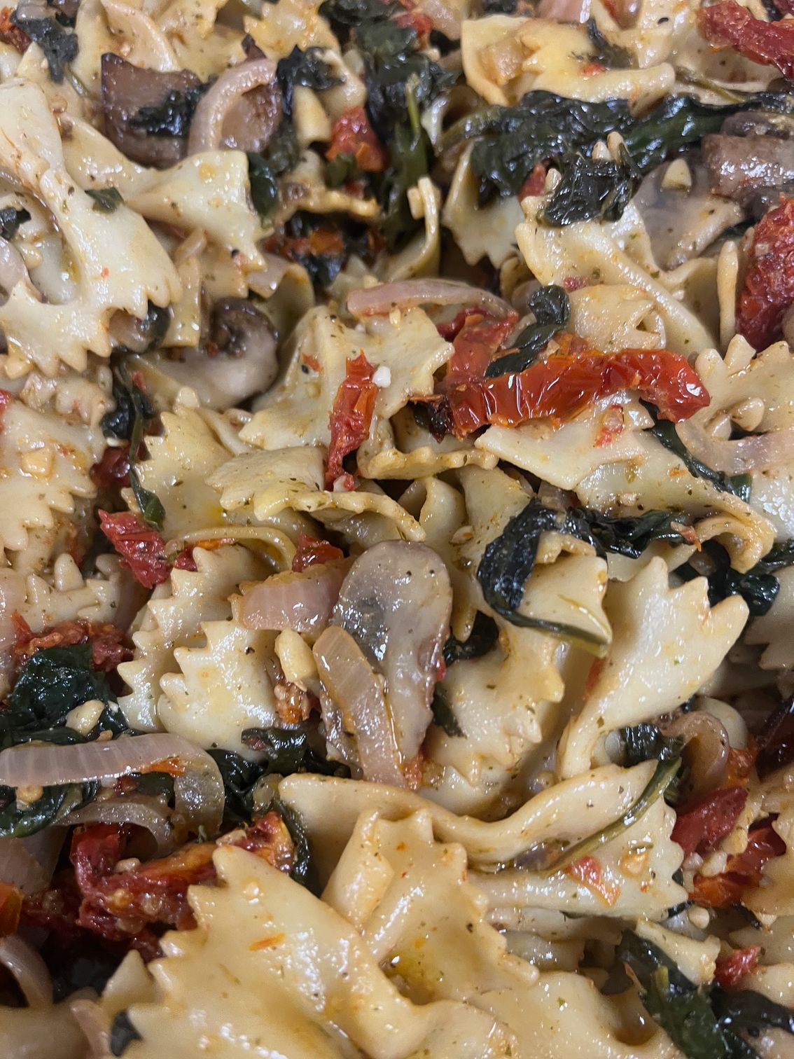 Pasta salad with sun-dried tomatoes, spinach, mushrooms, and onions.