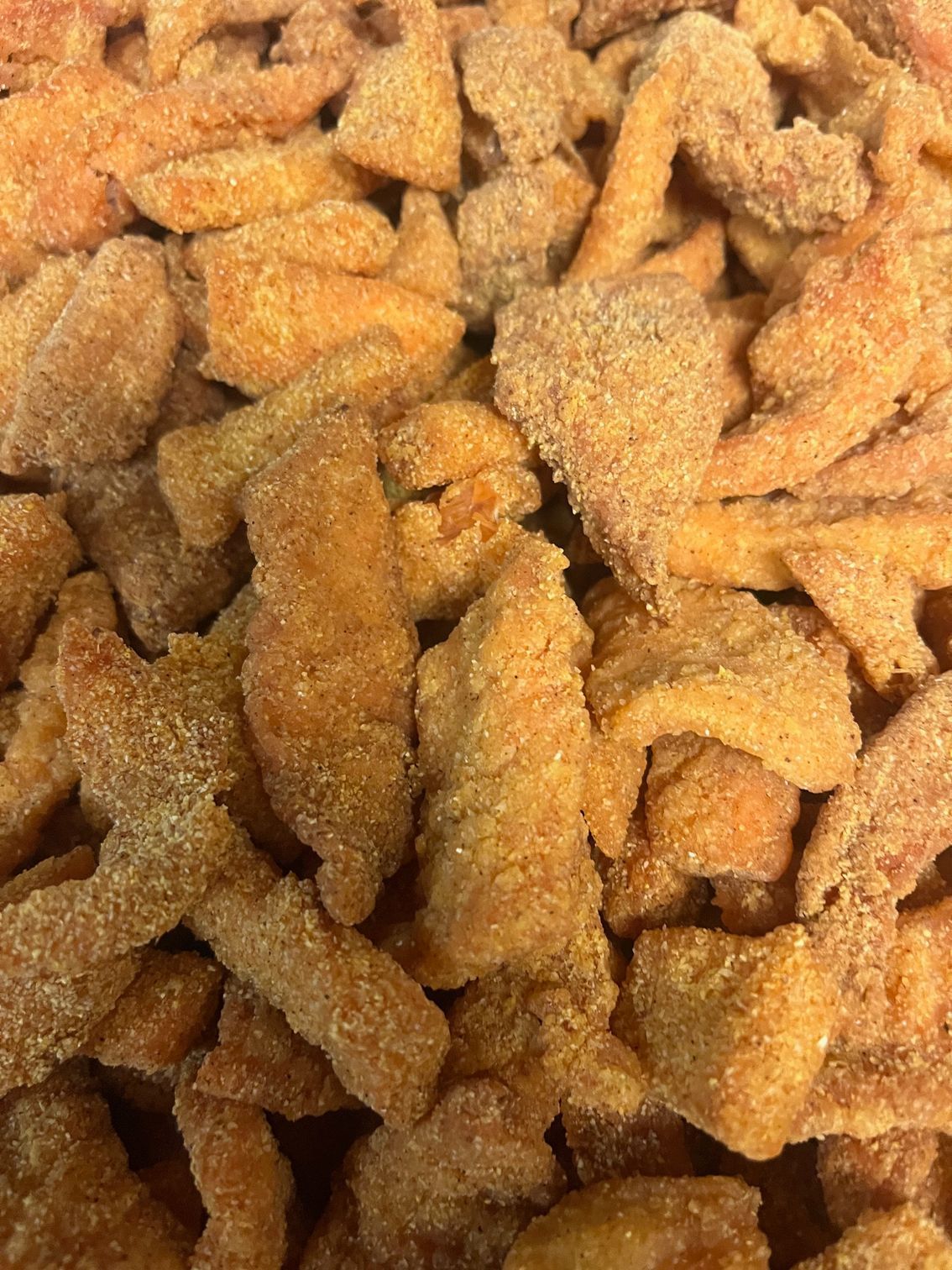 Close-up of a pile of golden-brown, sugared, fried chicken pieces.