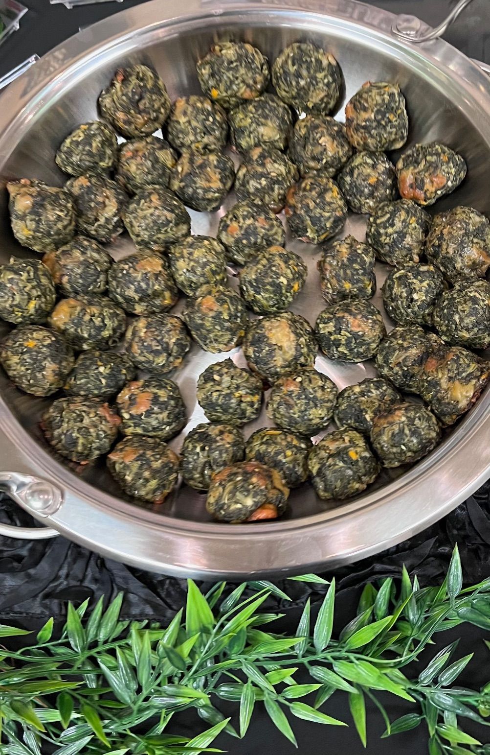A metal bowl overflowing with bite-sized, green-speckled food; possibly appetizers.