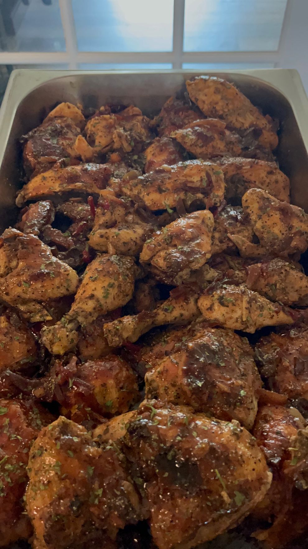 Tray of seasoned, cooked chicken pieces, including drumsticks, thighs, and breasts.