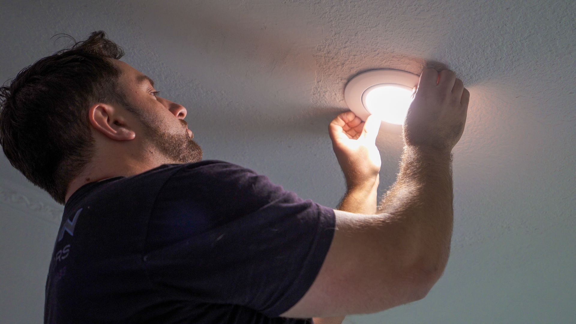 a man is changing a light bulb on the ceiling .