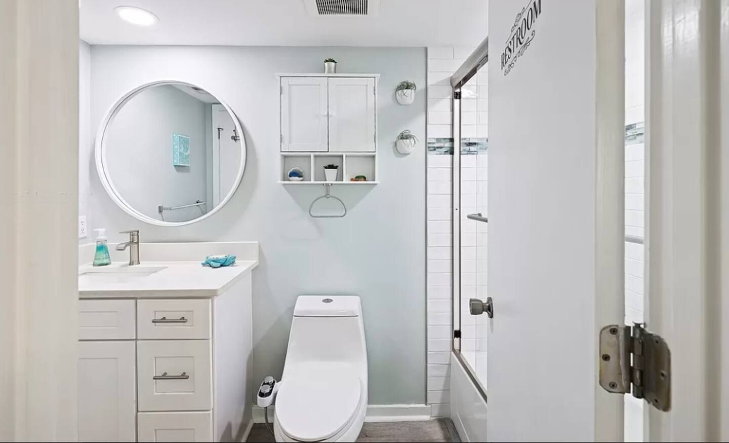 A fully accented modern bathroom with a toilet, sink, mirror and shower.