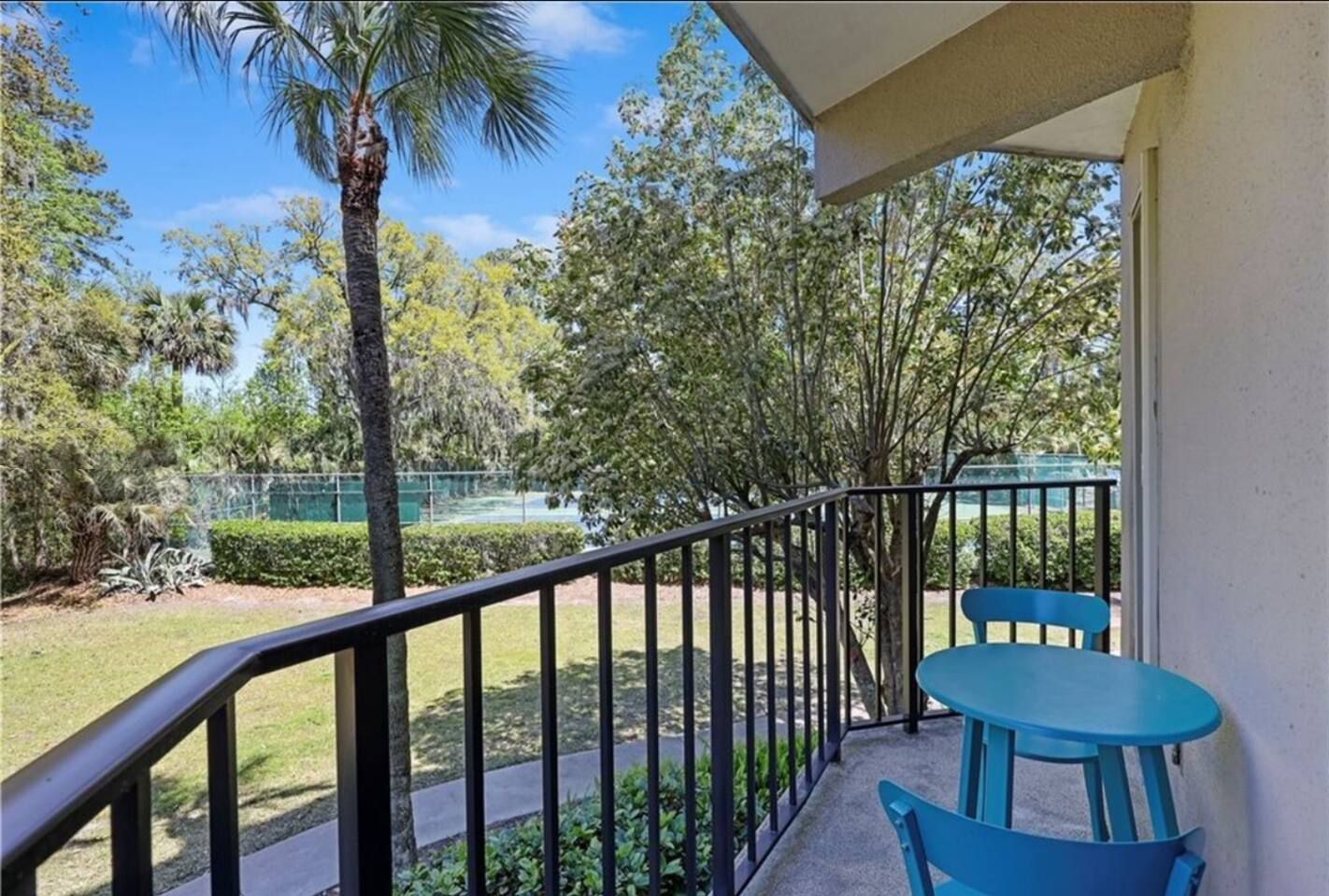 A balcony with a table and chairs and a palm tree in the background.
