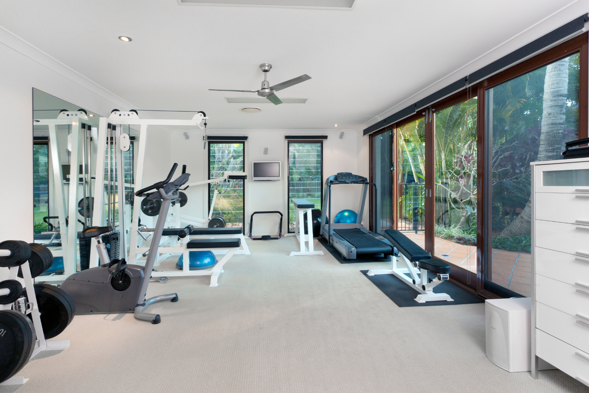 A home gym with a treadmill , exercise bike , dumbbells and a mirror.